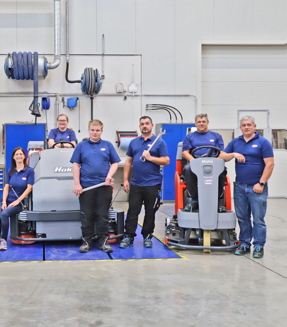 Teamfoto der Werkstatttechniker mit Bodenreinigungsmaschinen und Industriesauger